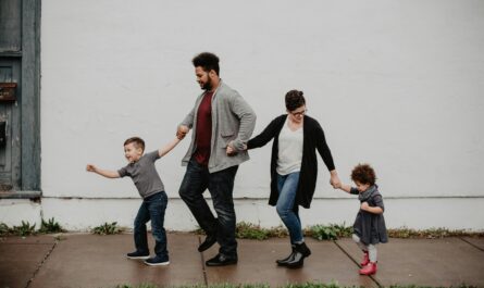 A joyful family walking together outdoors, holding hands in a playful and happy moment.